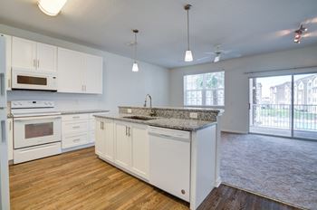 A kitchen and living room with a sliding glass door to a balcony